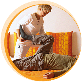 Ein Therapeut führt eine Massage oder Behandlung an einem liegenden Patienten durch.